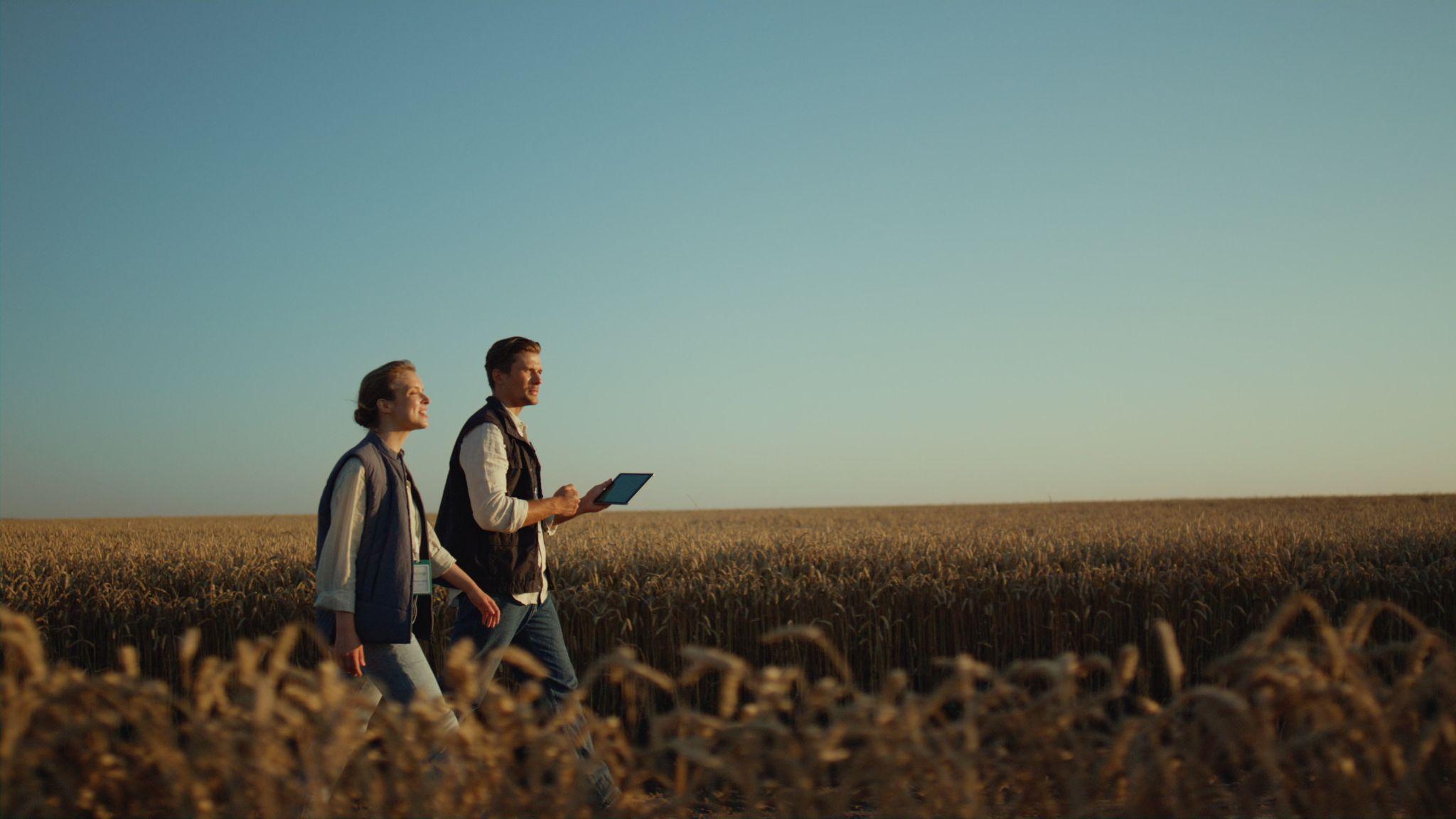 a man and a woman in matching black vests performing a farm appraisal
