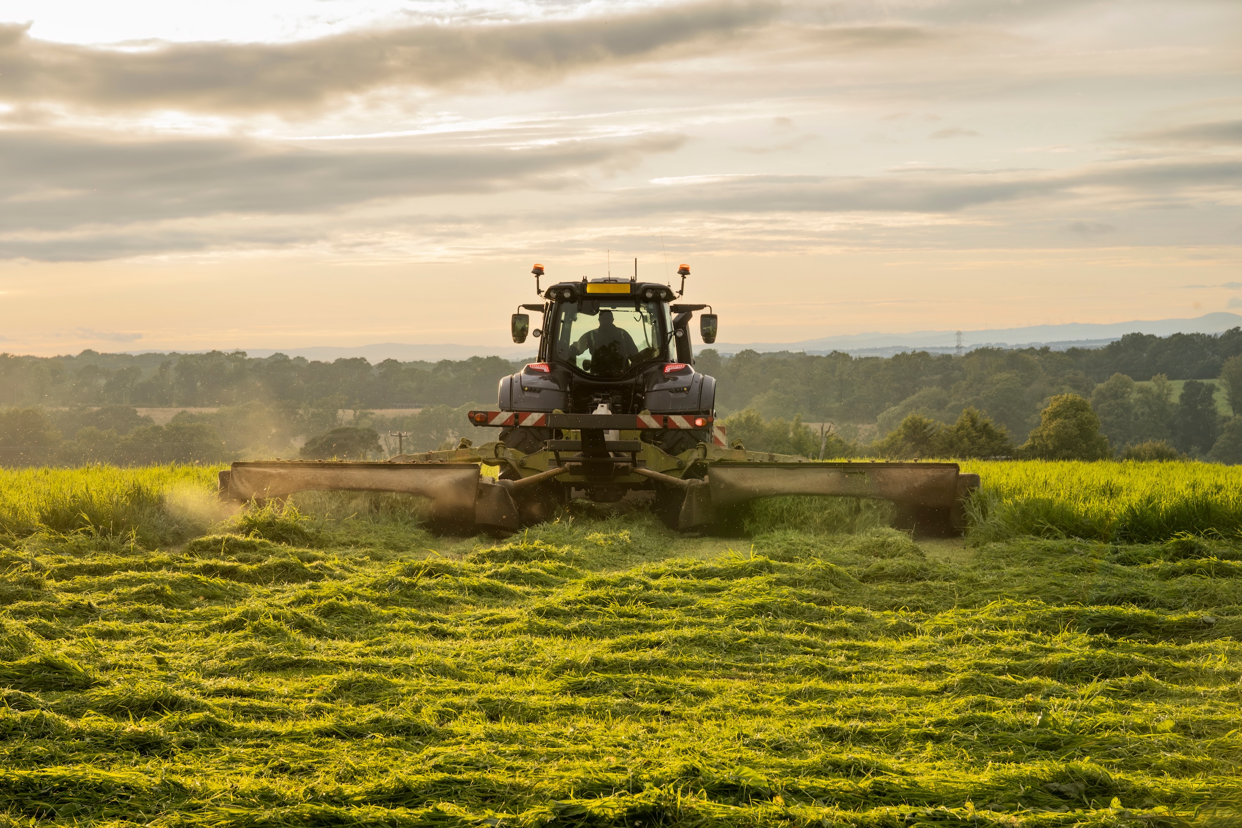 mower equipment mowing hay in a field on a small farm