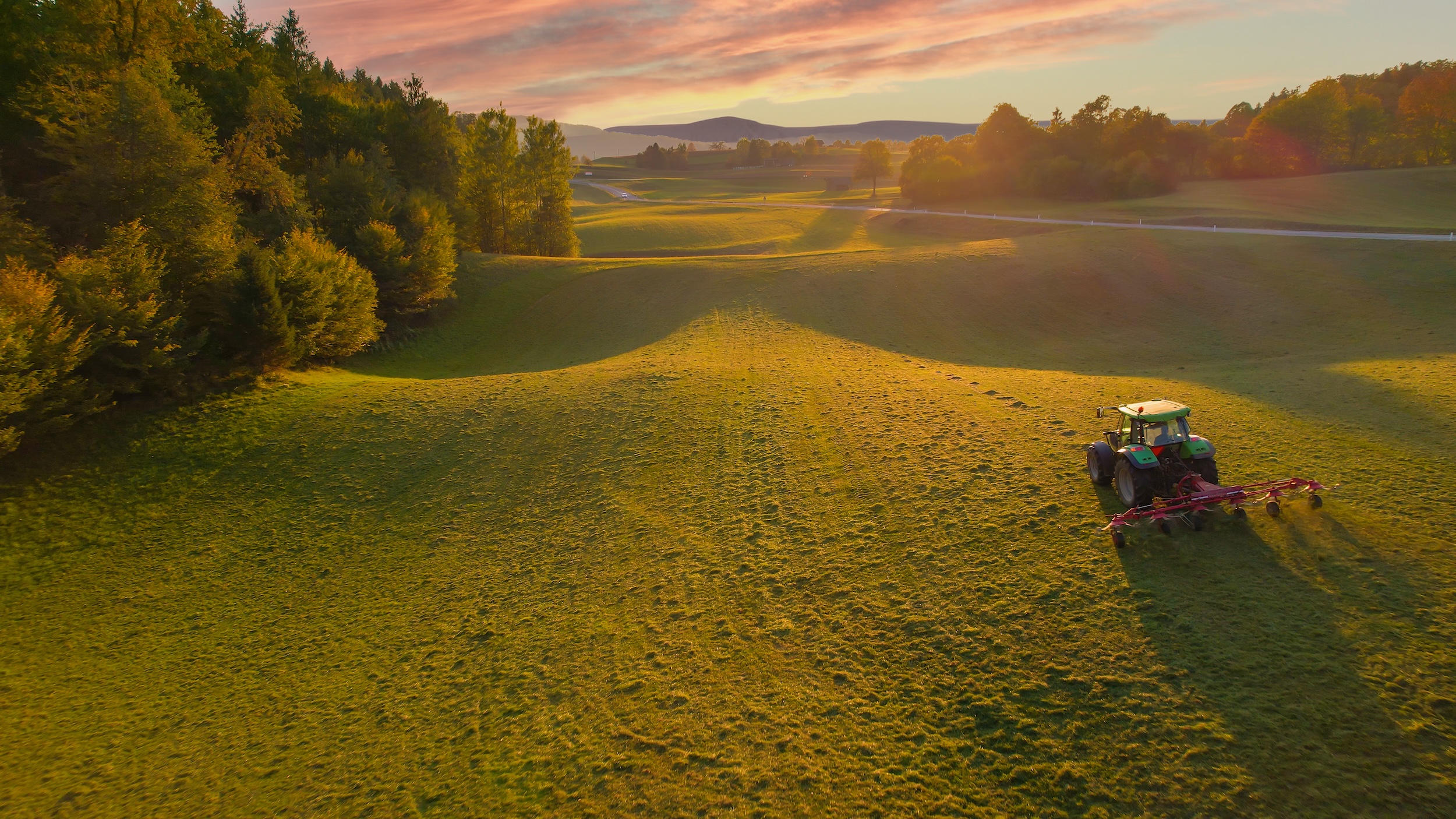tractor harvesting hay on a farm with rolling hills