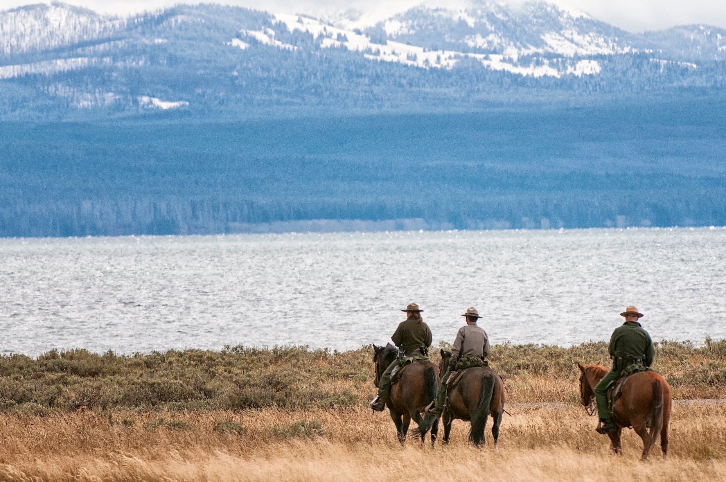 three horse rancher cowboys riding through the mountains while living on a ranch