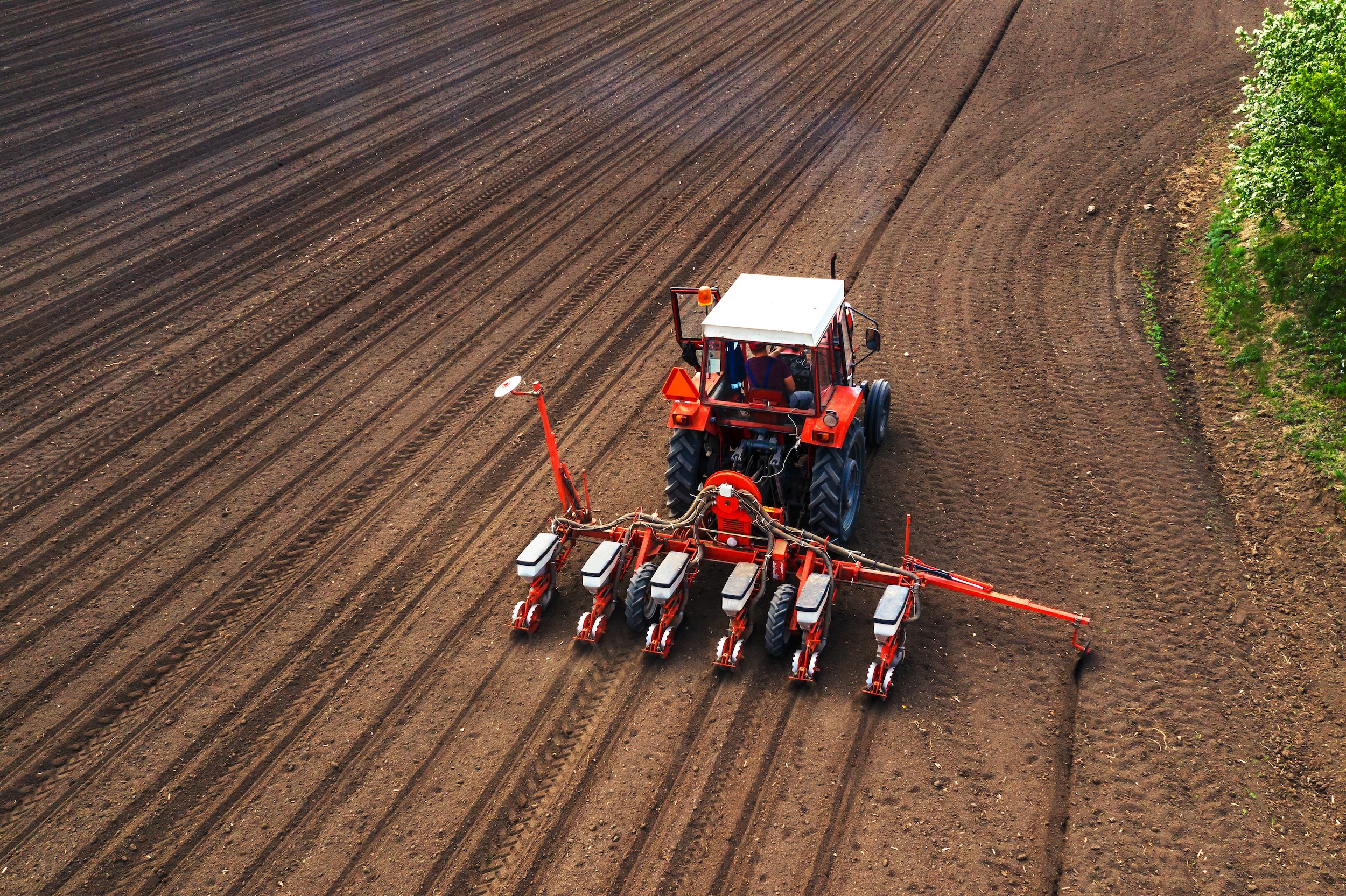 a tractor with high cost planting attachments driving over sections of dirt on a farm