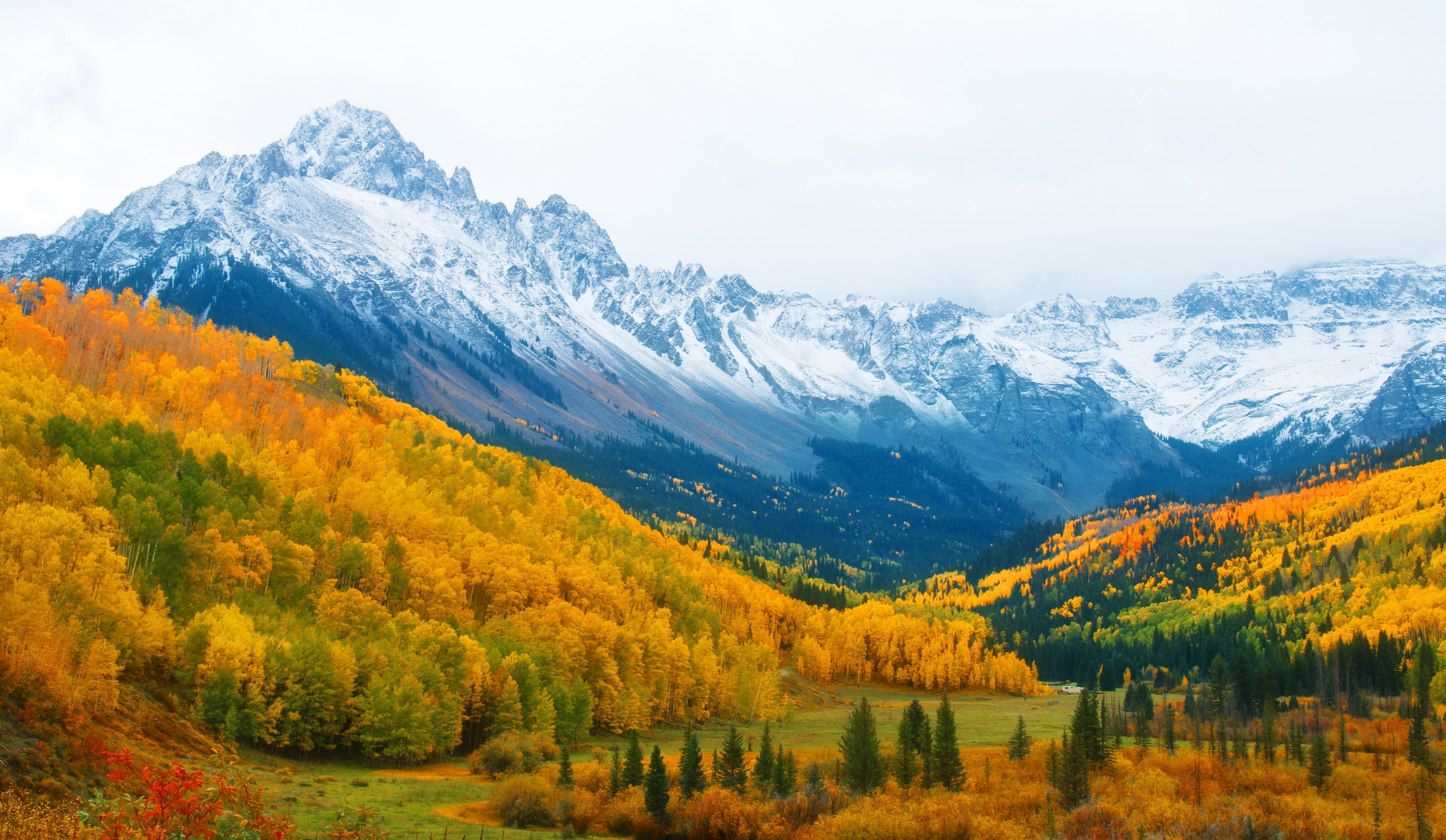 mountain land in the southwest section of the state of Colorado with snowy mountain tops and orange aspen trees at the base