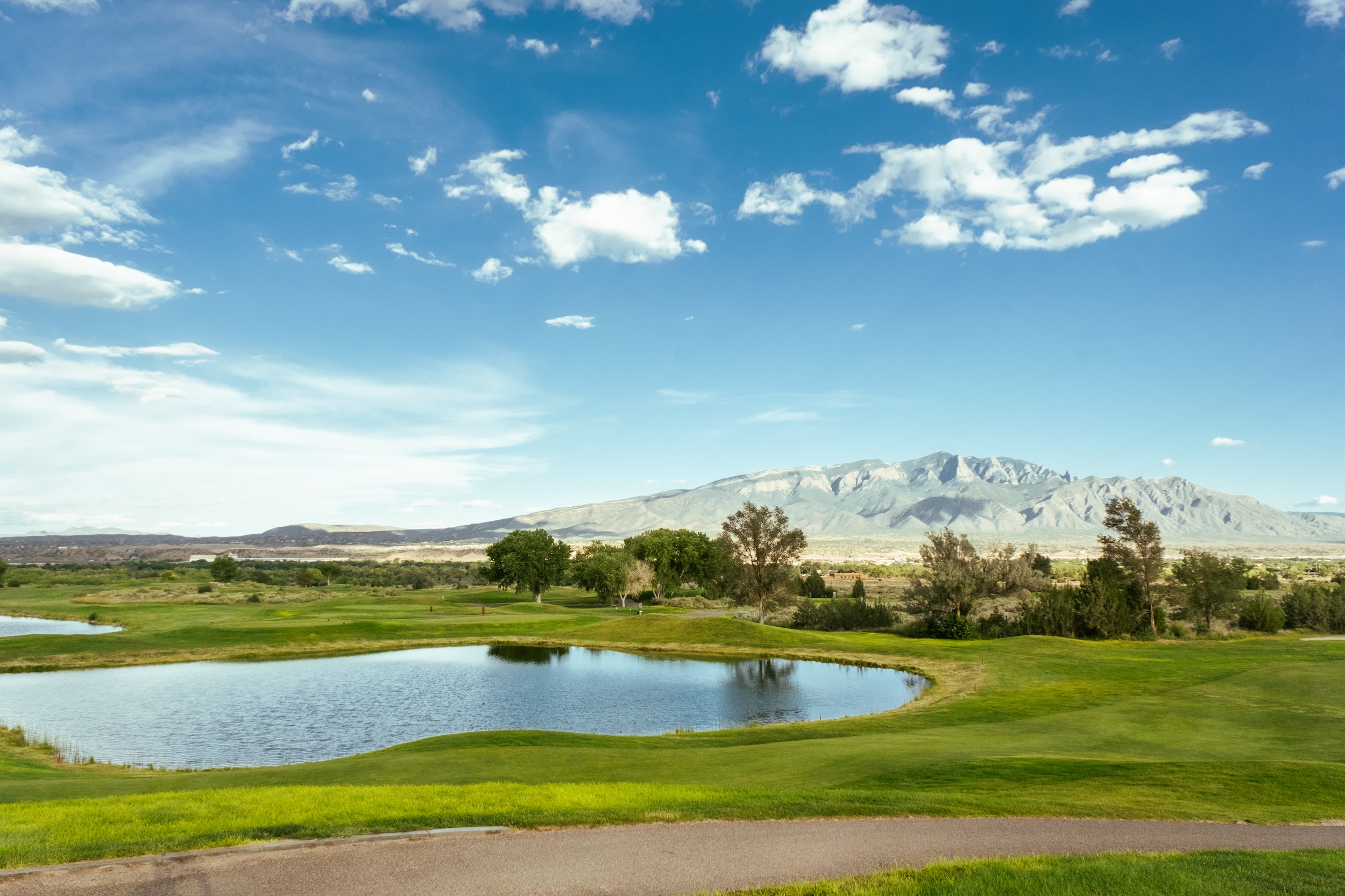 plot of land in the state of New Mexico with a lake in the foreground and mountains in the background