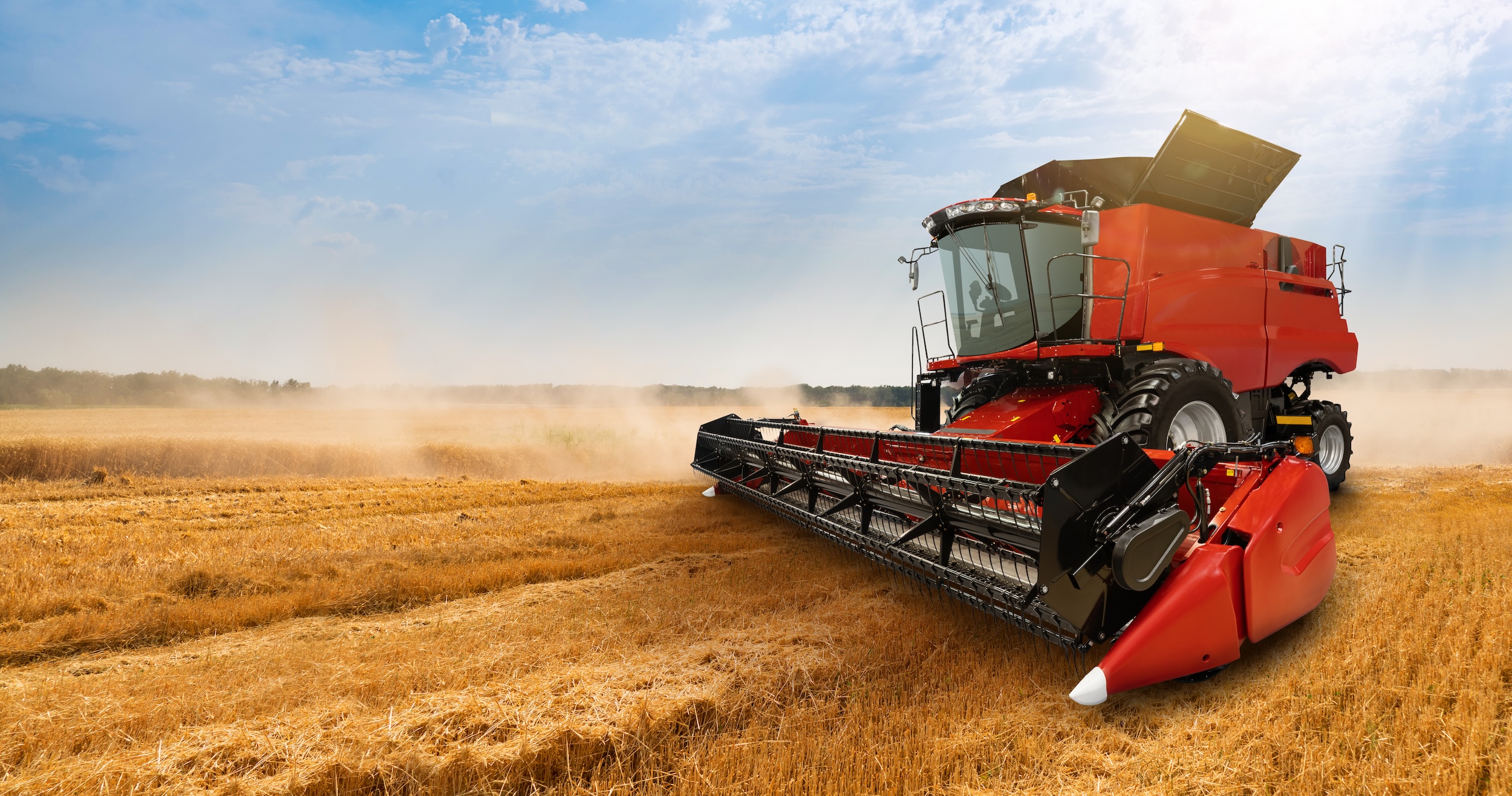 high price red combine harvester driving through a field