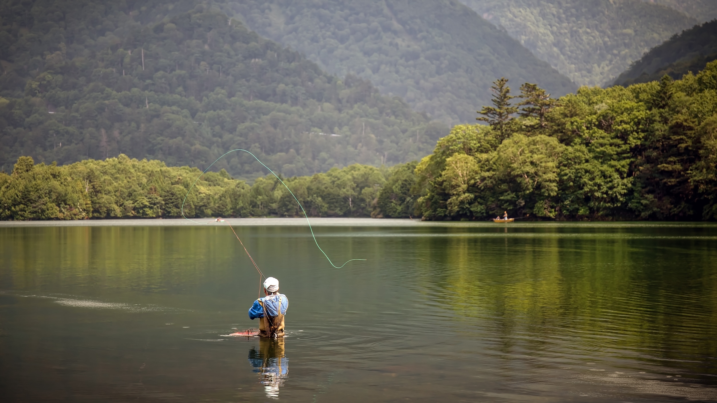 beginner fisherman wading into a stillwater lake and fly fishing