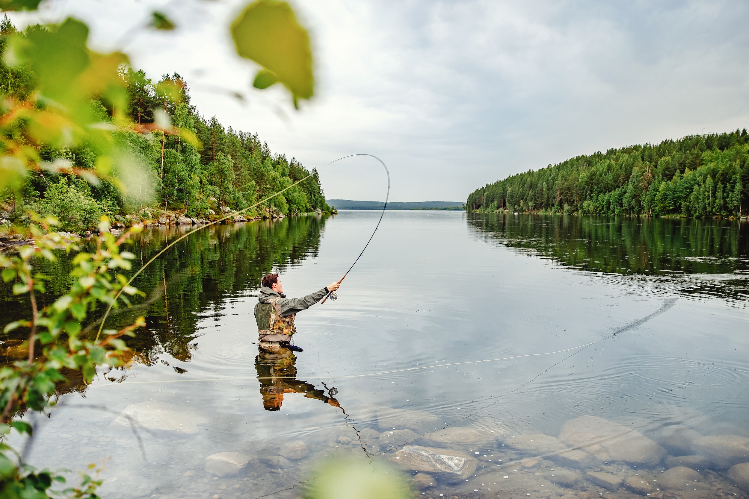 fisherman standing in stillwater showing the method for the overhead cast fly fishing technique