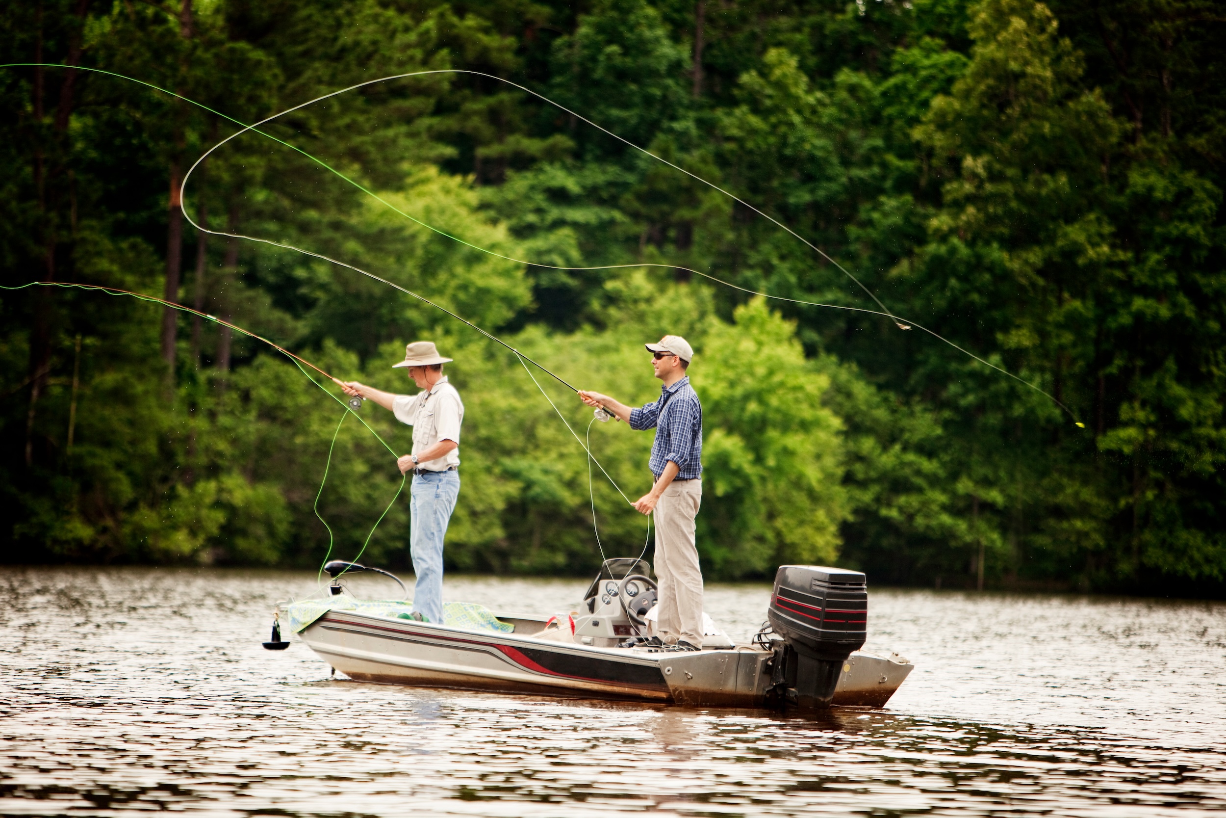 two men on a boat showing the overhead cast fly fishing technique