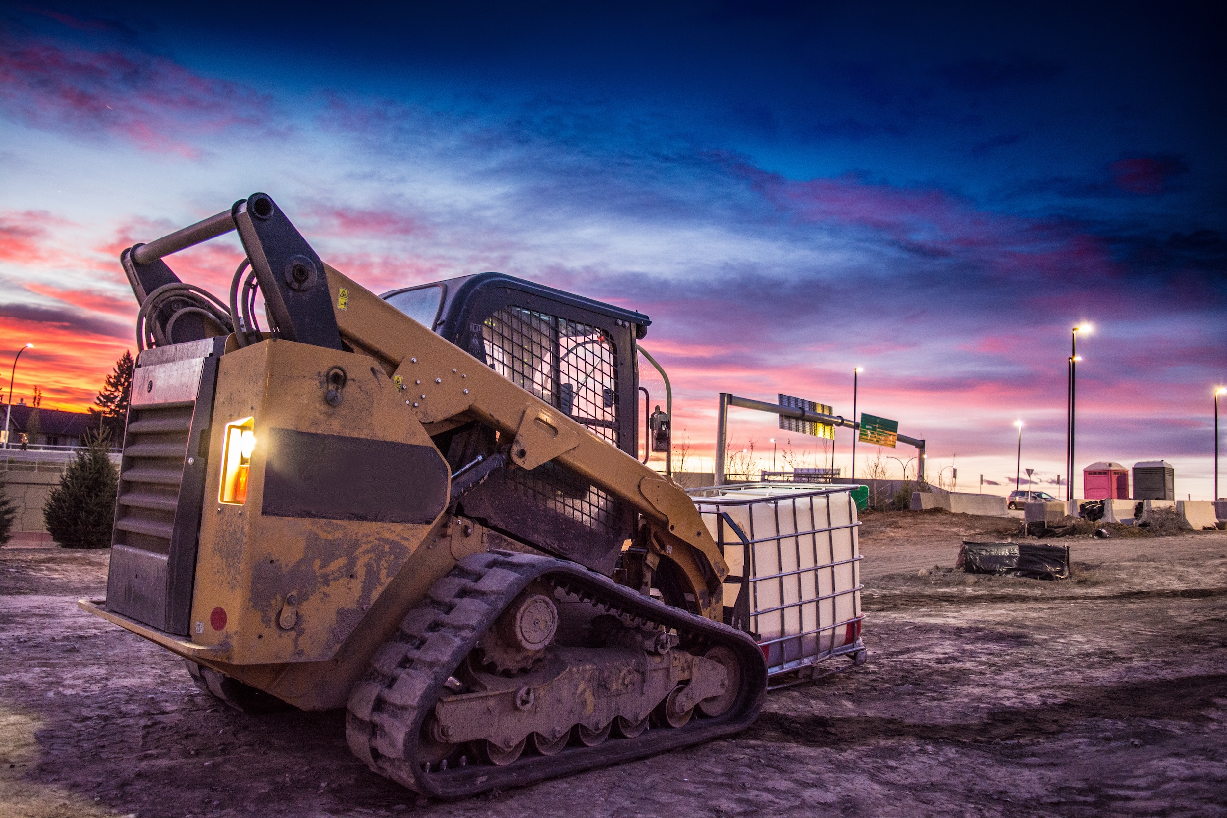 skid steer at dawn being used to haul water through a construction site