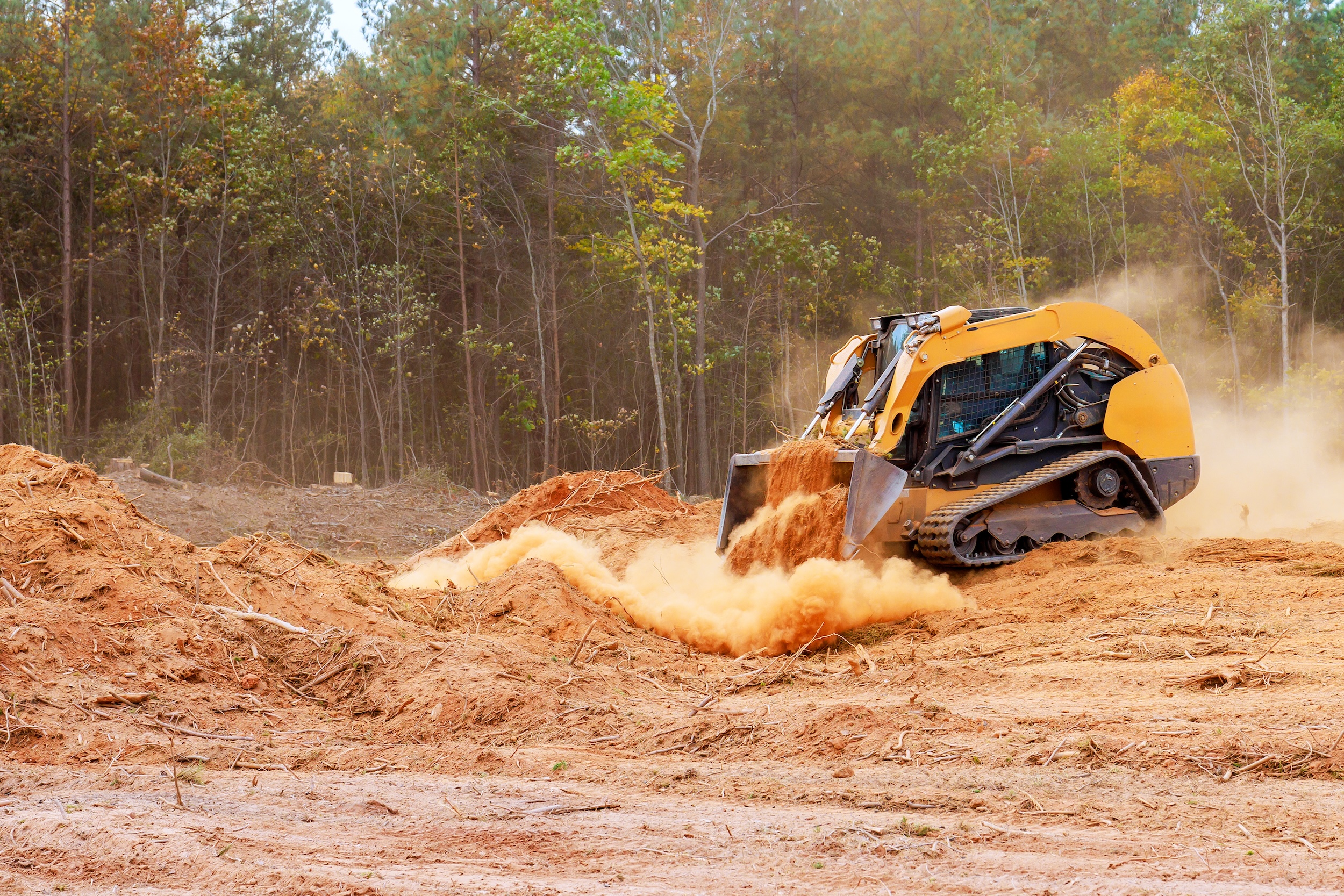 skid steer being used to move dirt on a piece of land in preparation for construction