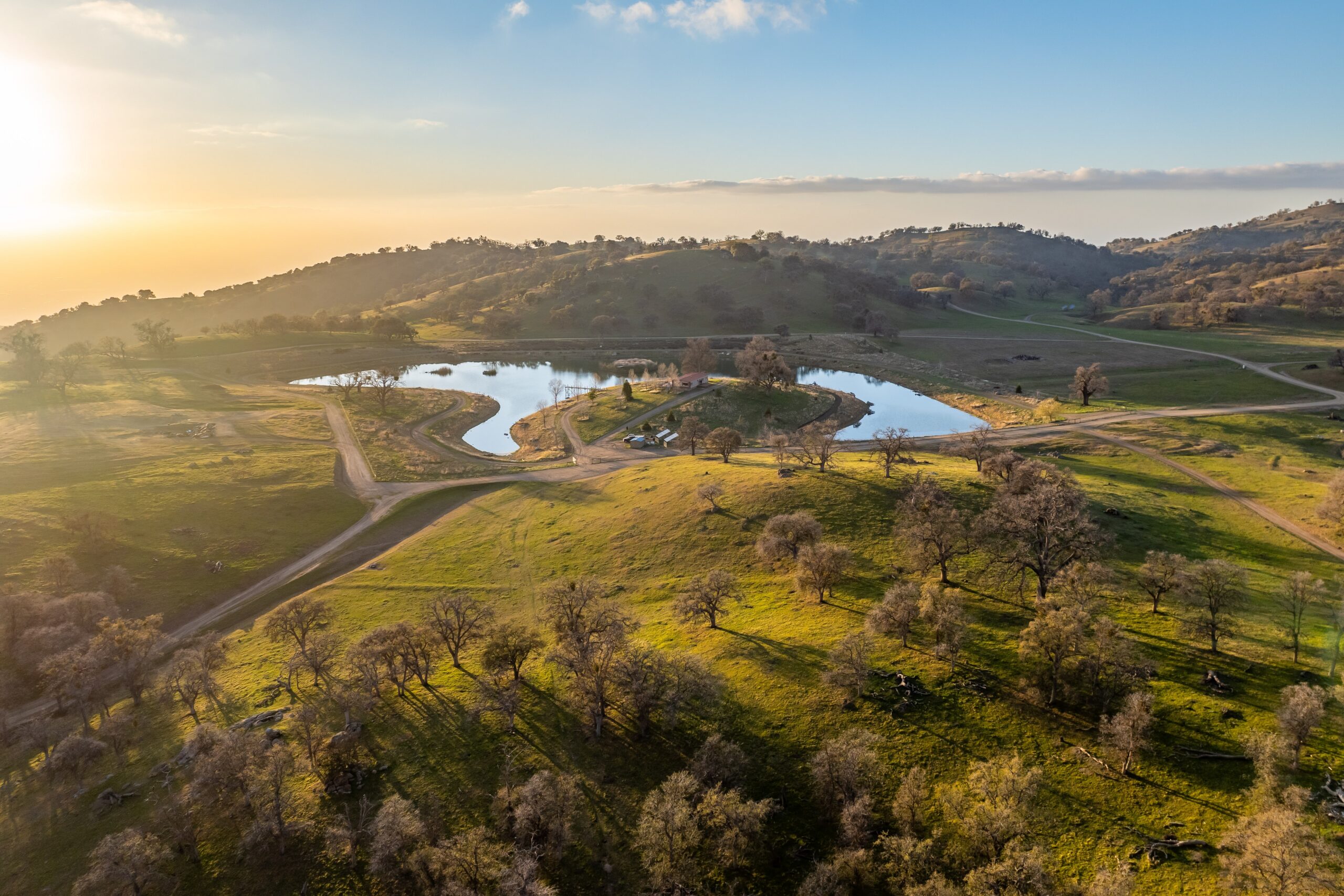California ranch on a hillside landscape featuring a pond