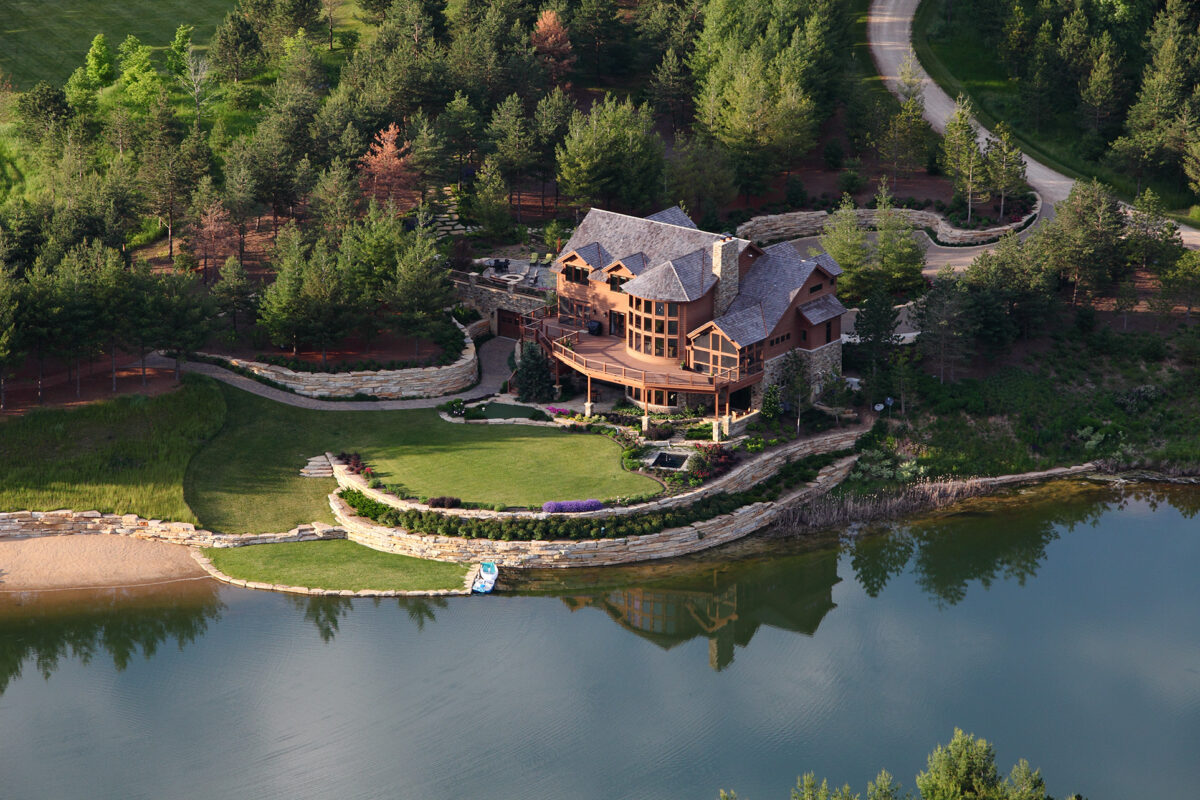 large home sitting on the shores of a private lake with wooded land surrounding it