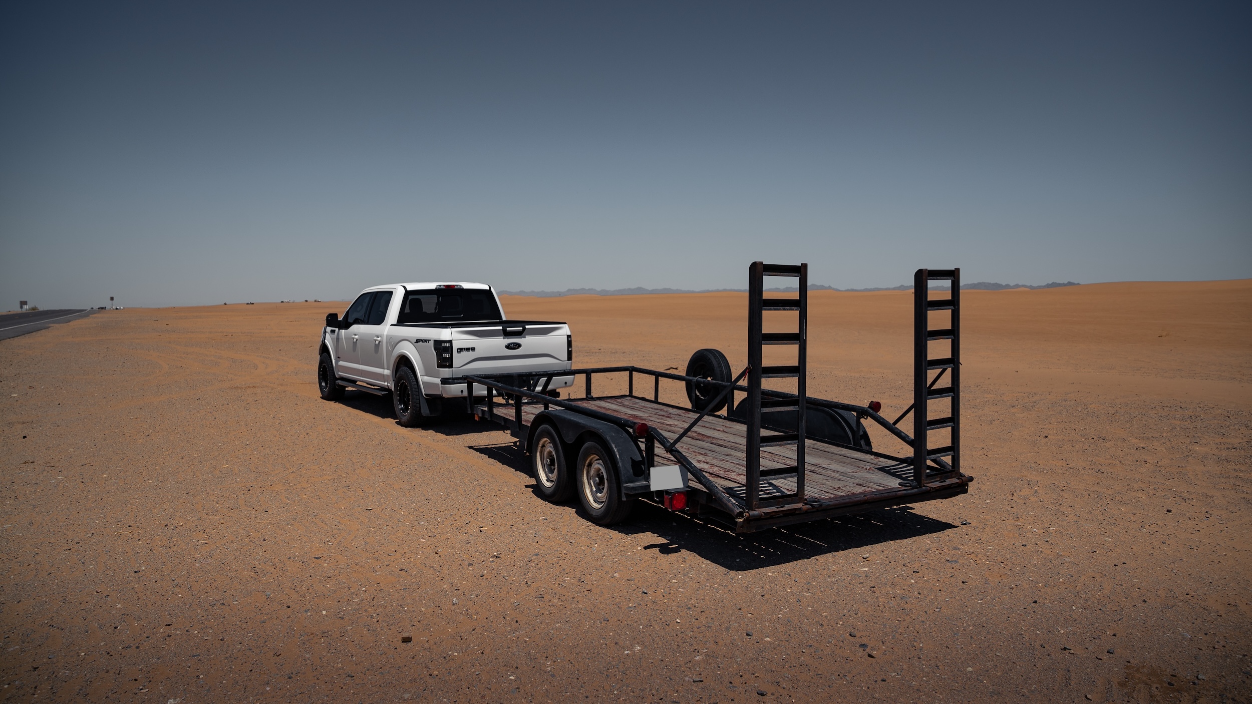 white pickup truck with an empty semi trailer hitched to the back