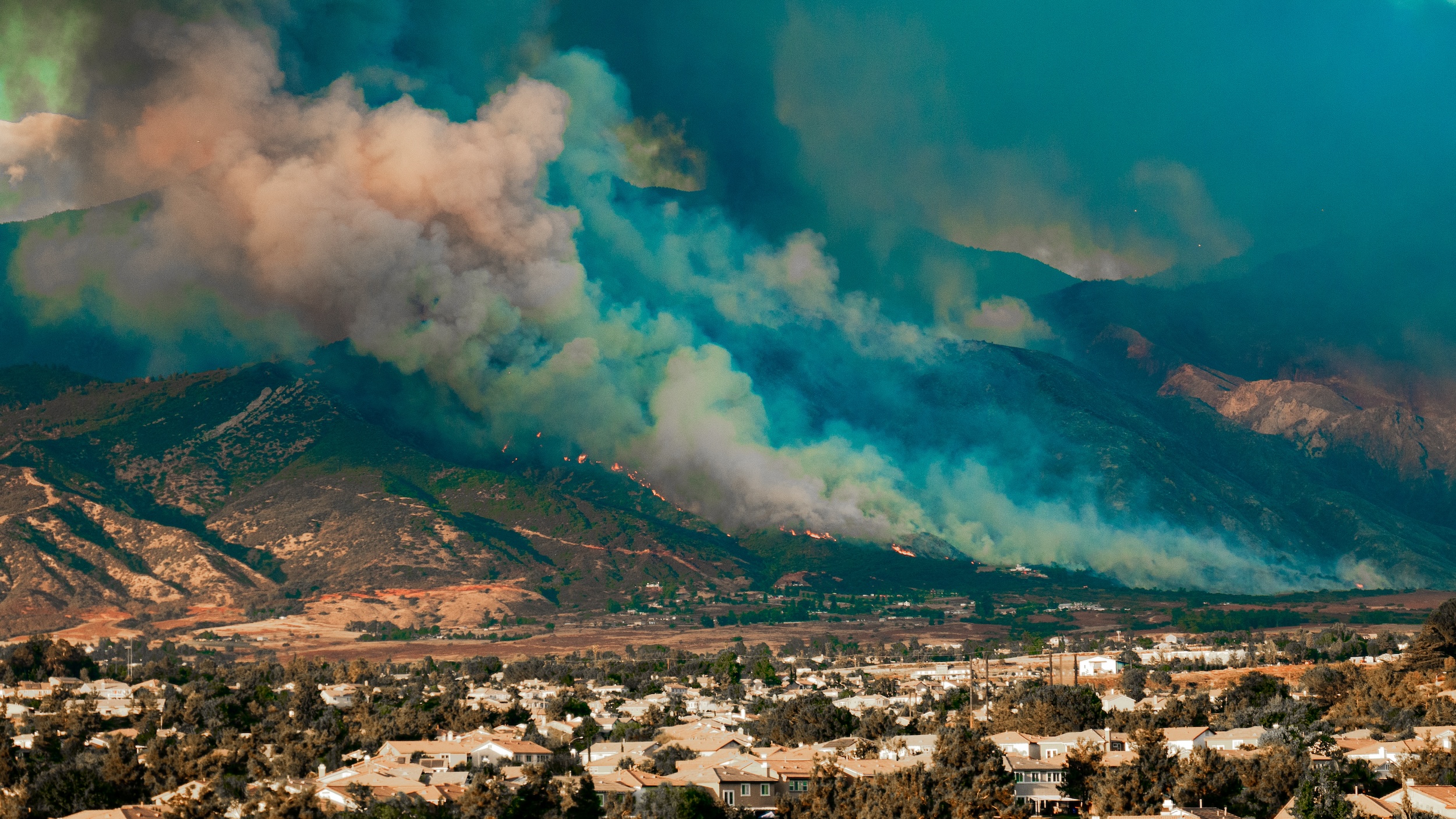 wildfire smoke rising up from the side of a mountain