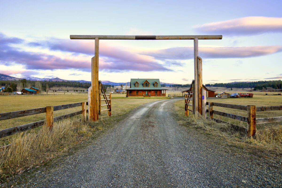 entrance gate and arch at the property line of a ranch style home on the open plains with mountains far in the background