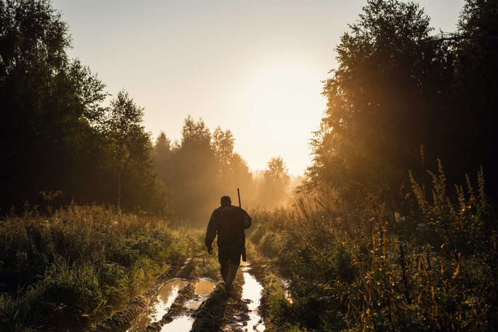 man with his hunting rifle walking through boggy ground