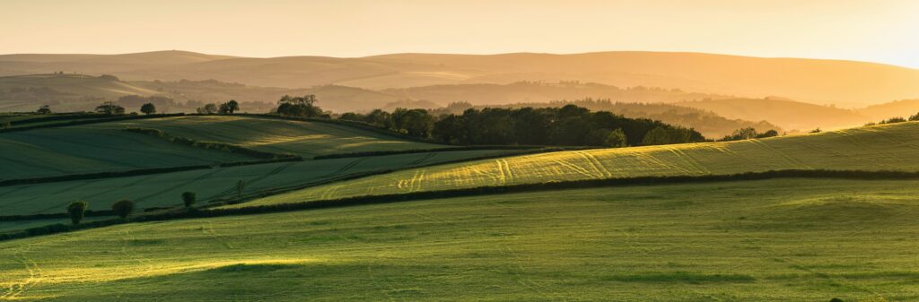 sun setting on rollings hills of land available. for buying at auction