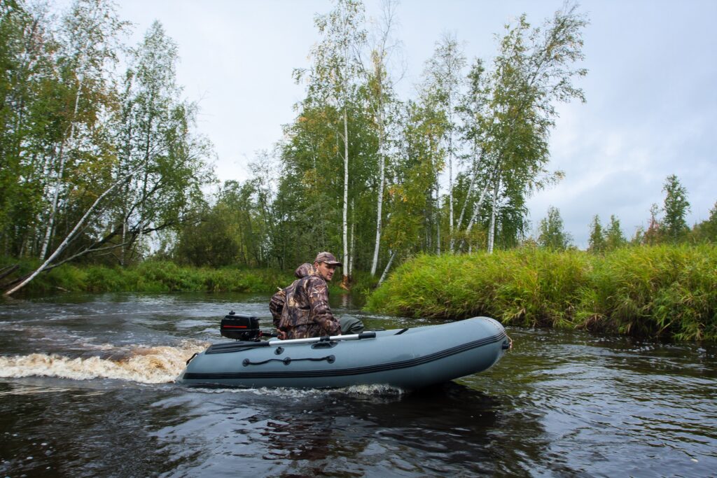 hunter in camoflauge riding in a boat scouting in advance of a duck hunting mission