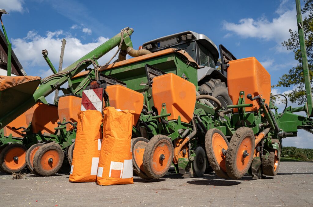 seed planter no till farming equipment with large orange bags of seeds in the foreground
