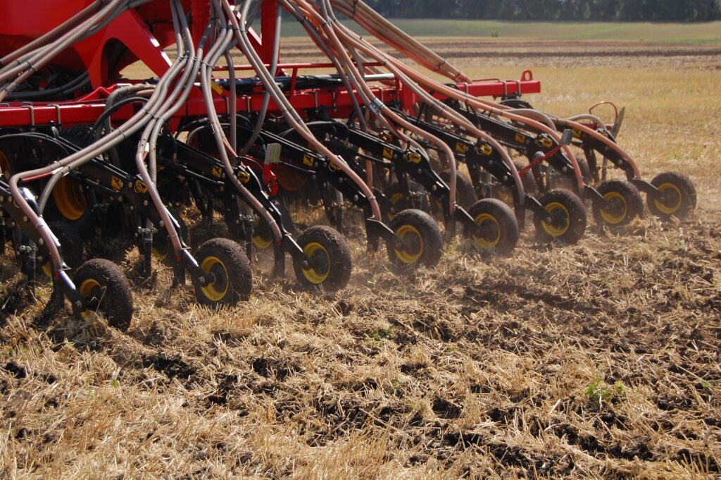 seed drill no till farming equipment making its way across a crop field