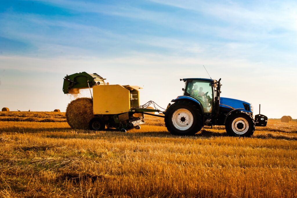 baler being used on a field to harvest hay