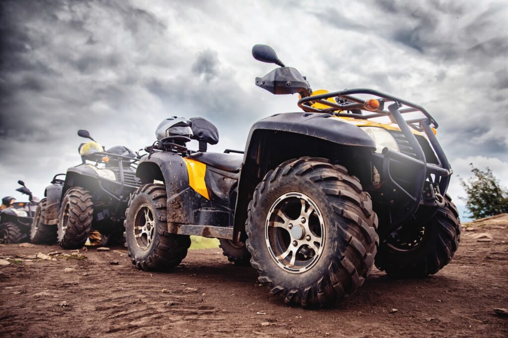 yellow atvs lined up on a dirt road with stormy clouds overhead