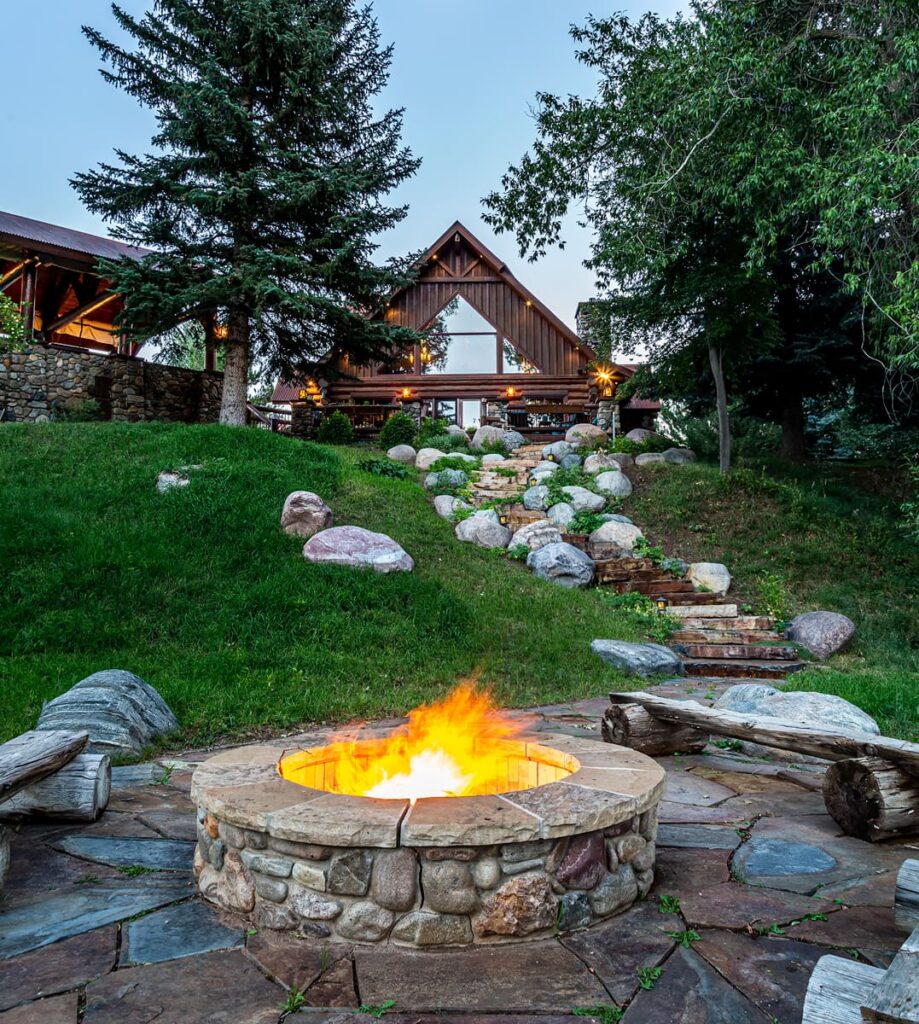 fire pit in front of a cabin style home on a hill being represented by a Hayden Outdoors selling real estate agent