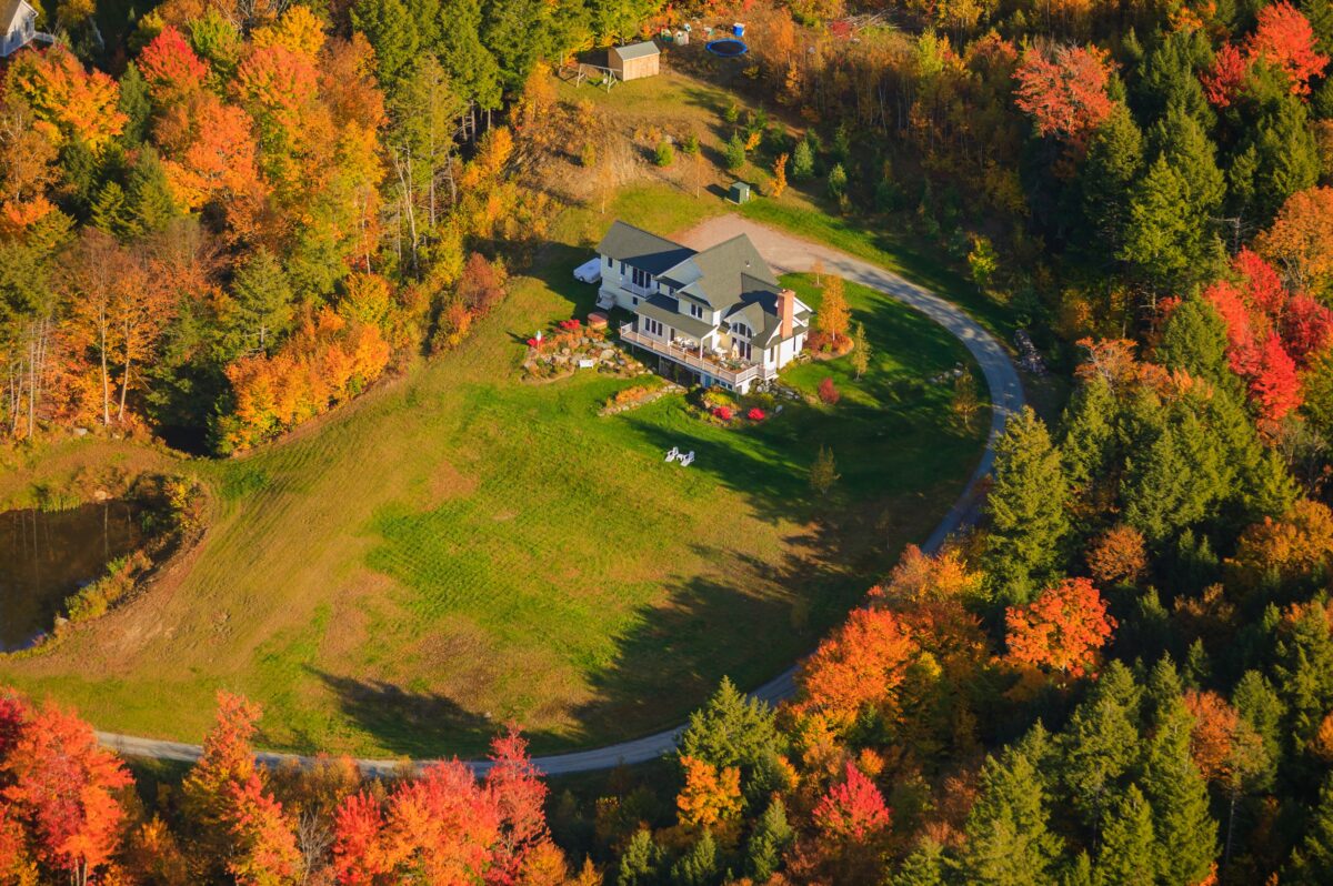 aerial view of home on rural real estate in a wooded area in New England during the fall