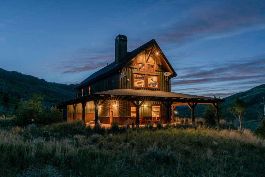 Colorado cabin style home in the mountains at night represented by a Hayden Outdoors selling real estate agent