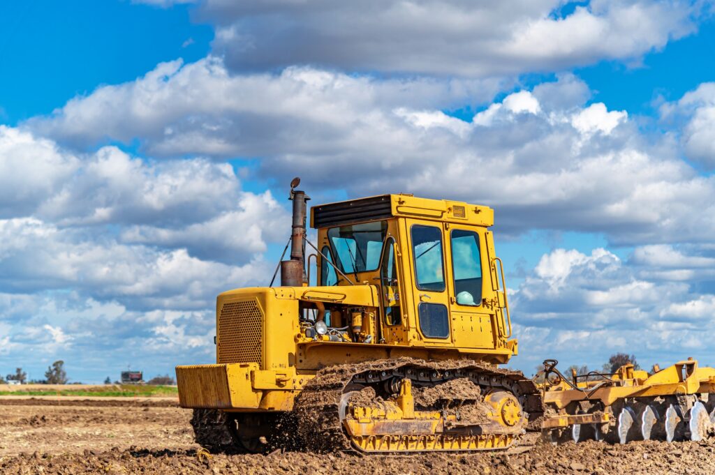 yellow bulldozer pulling a disc harrow