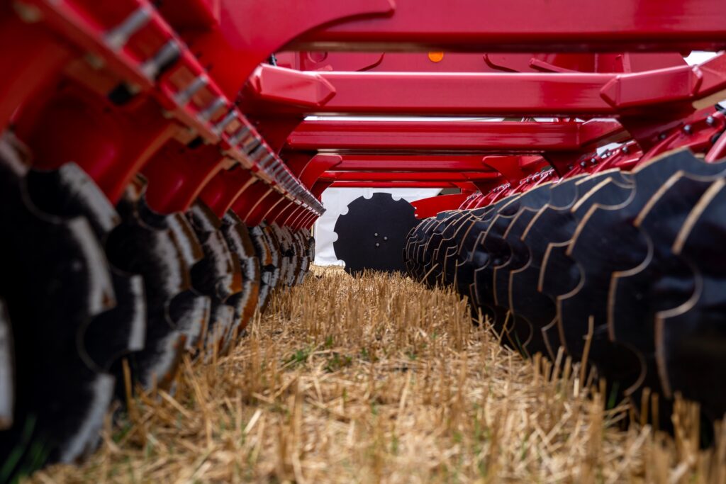 blades of a large disc harrow running across a wheat field