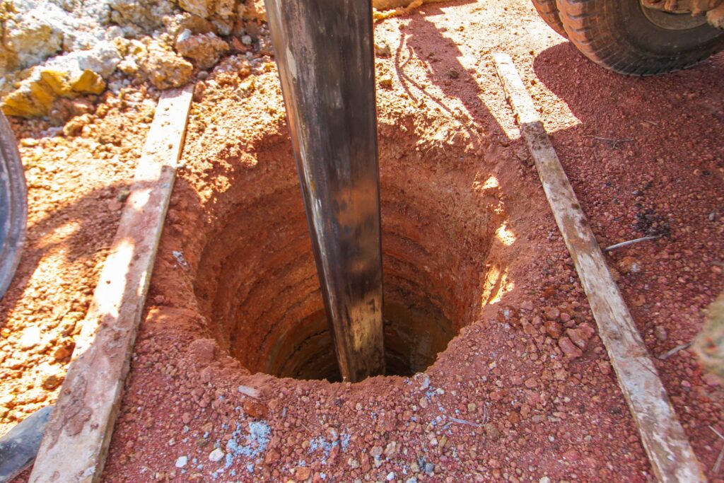 drilling equipment going into a section of drilled ground where a water well will be