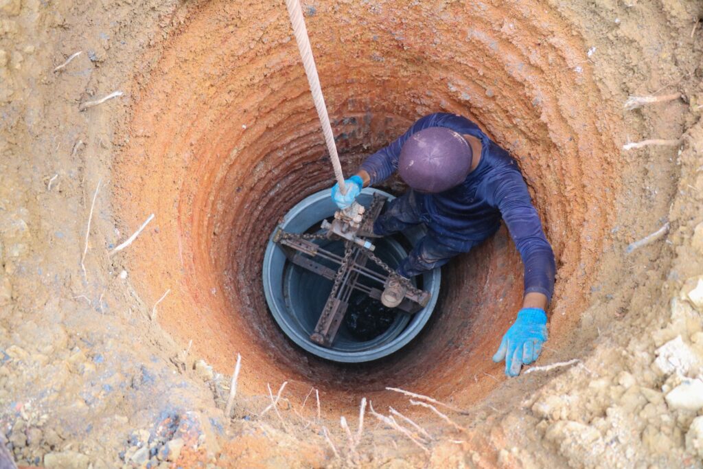 water well driller descending into a large well hole